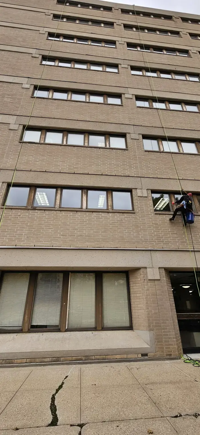 Technician on rope access cleaning upper-level commercial windows